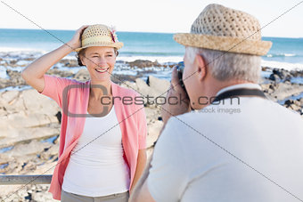Happy casual man taking a photo of partner by the sea