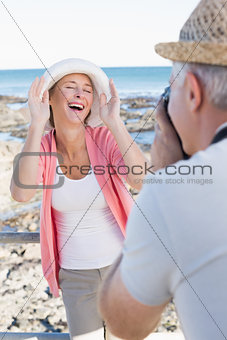 Happy casual man taking a photo of partner by the sea