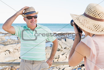 Happy casual woman taking photo of her partner by the coast