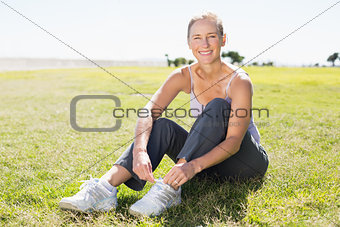 Fit mature woman tying her lace on the grass