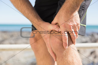 Fit man gripping his injured knee