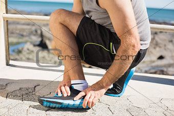 Fit man gripping his injured ankle