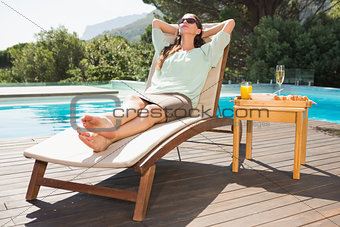 Woman relaxing by pool with breakfast on table