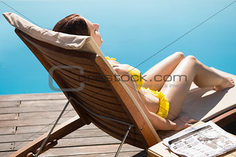 Woman in bikini relaxing by swimming pool