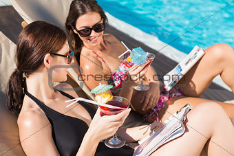Women with drinks by swimming pool