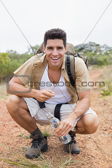 Cheerful hiking man crouching on mountain terrain