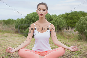 Woman sitting in lotus position on countryside landscape
