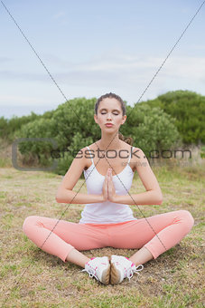 Woman with hands joined sitting on countryside landscape