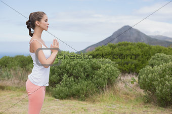 Woman with hands joined standing on countryside landscape