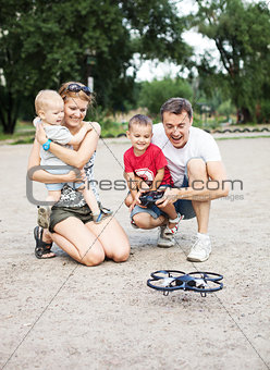 Young family with two boys playing with RC quadrocopter toy