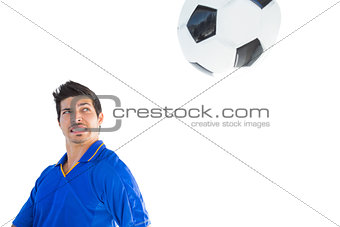 Football player in blue jumping to ball