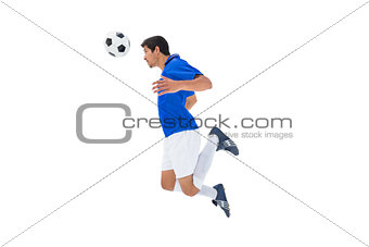 Football player in blue jumping to ball