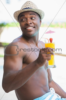 Smiling man in swimming trunks holding a cocktail