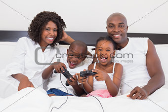 Happy family playing video games together in bed