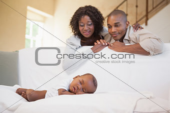 Baby boy sleeping peacefully on couch watched by parents