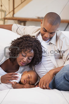 Baby boy sleeping peacefully on couch with happy parents