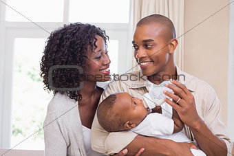 Happy parents feeding their baby boy a bottle