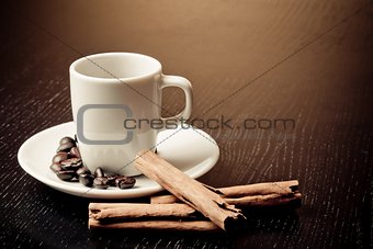white cup with coffee near coffee beans over wood table