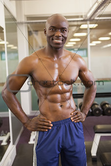 Smiling shirtless muscular man with hands on hips