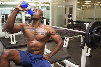 Muscular man drinking energy drink in gym