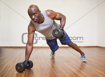 Muscular man doing push ups with dumbbells in gym