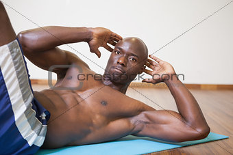 Muscular man doing abdominal crunches in gym