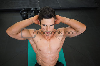 Muscular man doing abdominal crunches in gym