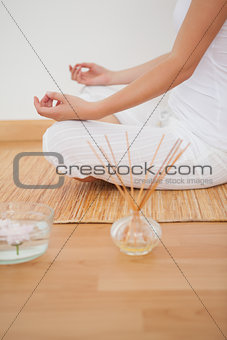 Peaceful woman sitting in lotus pose on bamboo mat