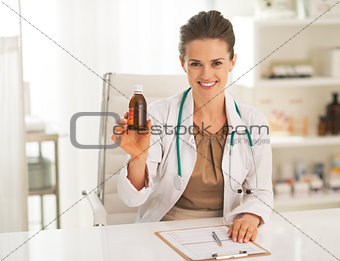 Smiling doctor woman showing medicine bottle