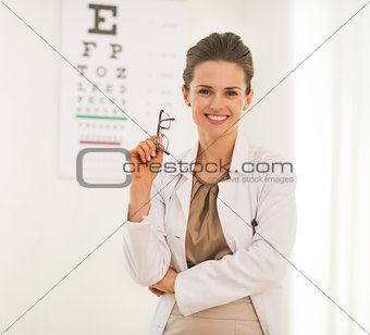 Portrait of doctor woman with eyeglasses in front of snellen cha