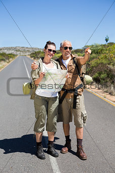 Hiking couple looking at map on the road and pointing ahead