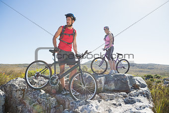 Fit cyclist couple standing at the summit looking around