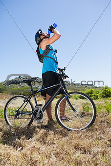 Fit cyclist riding in the countryside taking a drink