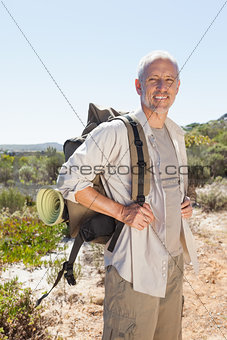 Handsome hiker smiling at camera in the countryside