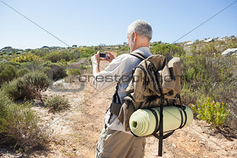 Handsome hiker taking a photo in the countryside