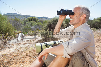 Hiker taking a break on country trail looking through binoculars