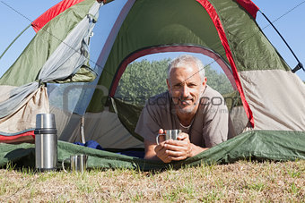 Happy camper smiling at camera lying in his tent