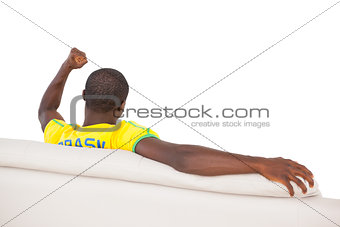 Man sitting on sofa and cheering