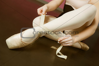 Ballerina tying the ribbon on her ballet slippers