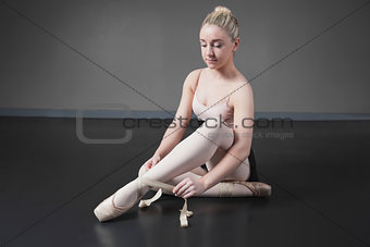 Pretty ballerina tying the ribbon on her ballet slippers
