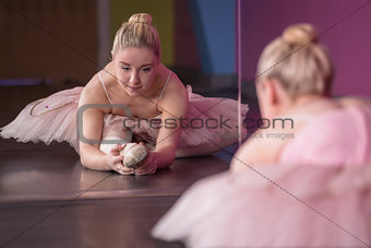 Graceful ballerina warming up in front of mirror