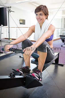 Fit smiling brunette working out on rowing machine