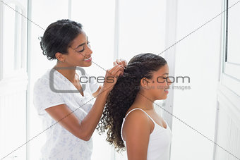 Pretty mother tying her daughters hair back