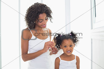 Pretty mother brushing her daughters hair