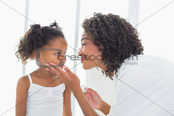 Pretty mother touching her daughters face lovingly
