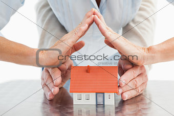 Couples hands with model house