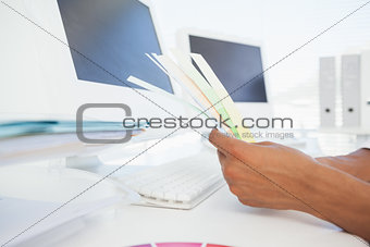 Designer working at desk holding colour samples