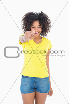Pretty girl in yellow tshirt and denim hot pants pointing at camera
