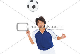 Football player in blue heading the ball