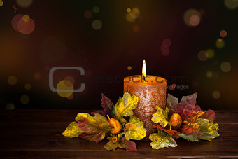 Autumn arrangement with candle against defocused holiday lights